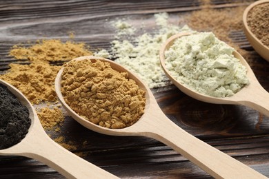 Photo of Different superfood powders and spoons on wooden table, closeup