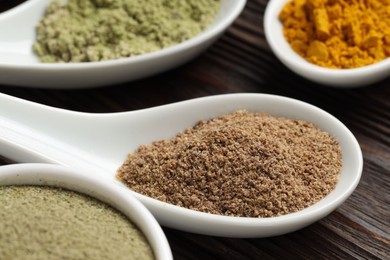 Photo of Different superfood powders in spoons on wooden table, closeup