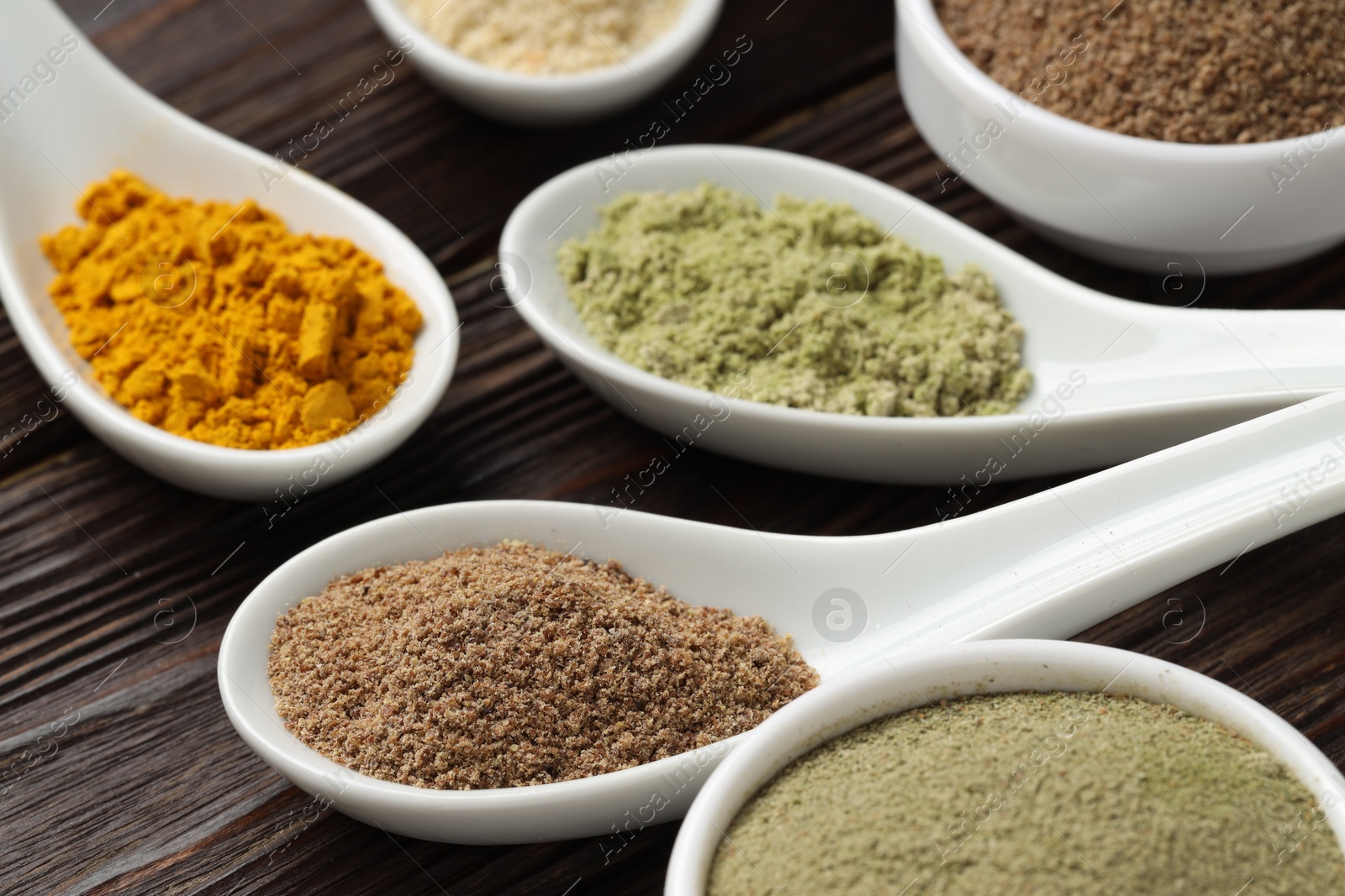 Different superfood powders in spoons on wooden table, closeup Photo of Different superfood powders in spoons on wooden table, closeup