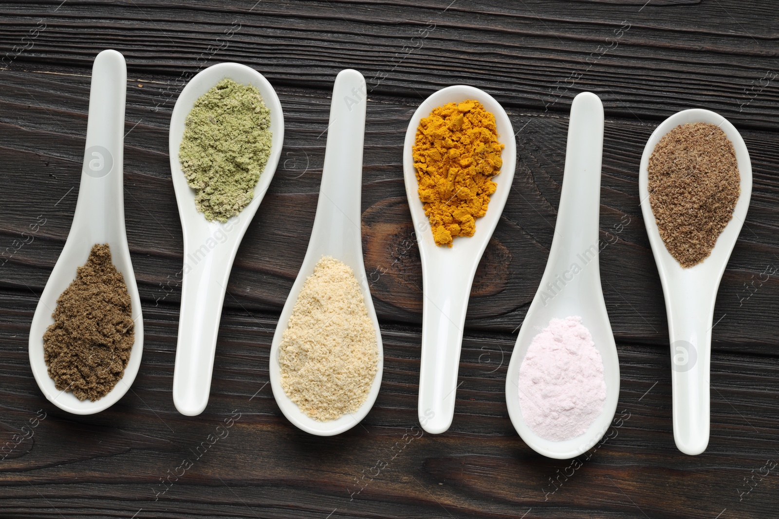 Different superfood powders in spoons on wooden table, flat lay Photo of Different superfood powders in spoons on wooden table, flat lay