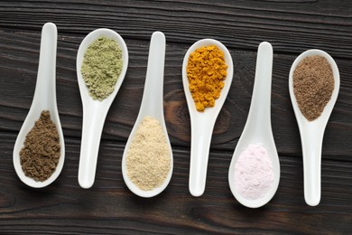 Photo of Different superfood powders in spoons on wooden table, flat lay