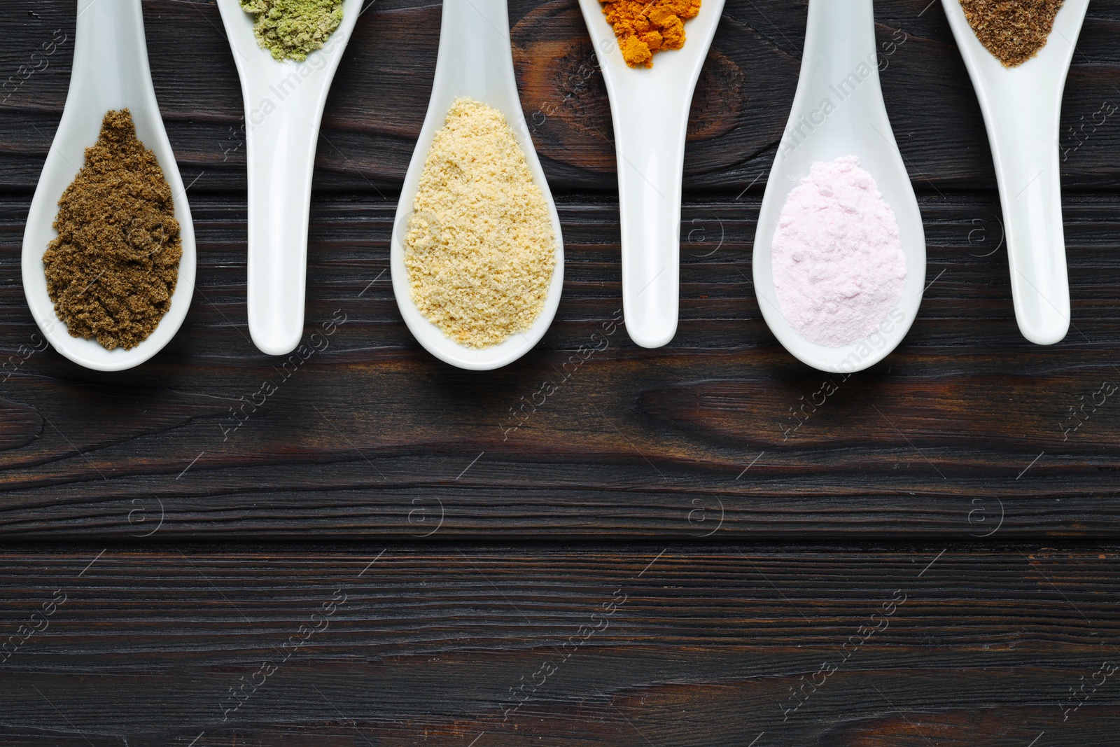 Different superfood powders in spoons on wooden table, flat lay. Space for text Photo of Different superfood powders in spoons on wooden table, flat lay. Space for text