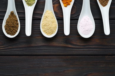 Photo of Different superfood powders in spoons on wooden table, flat lay. Space for text