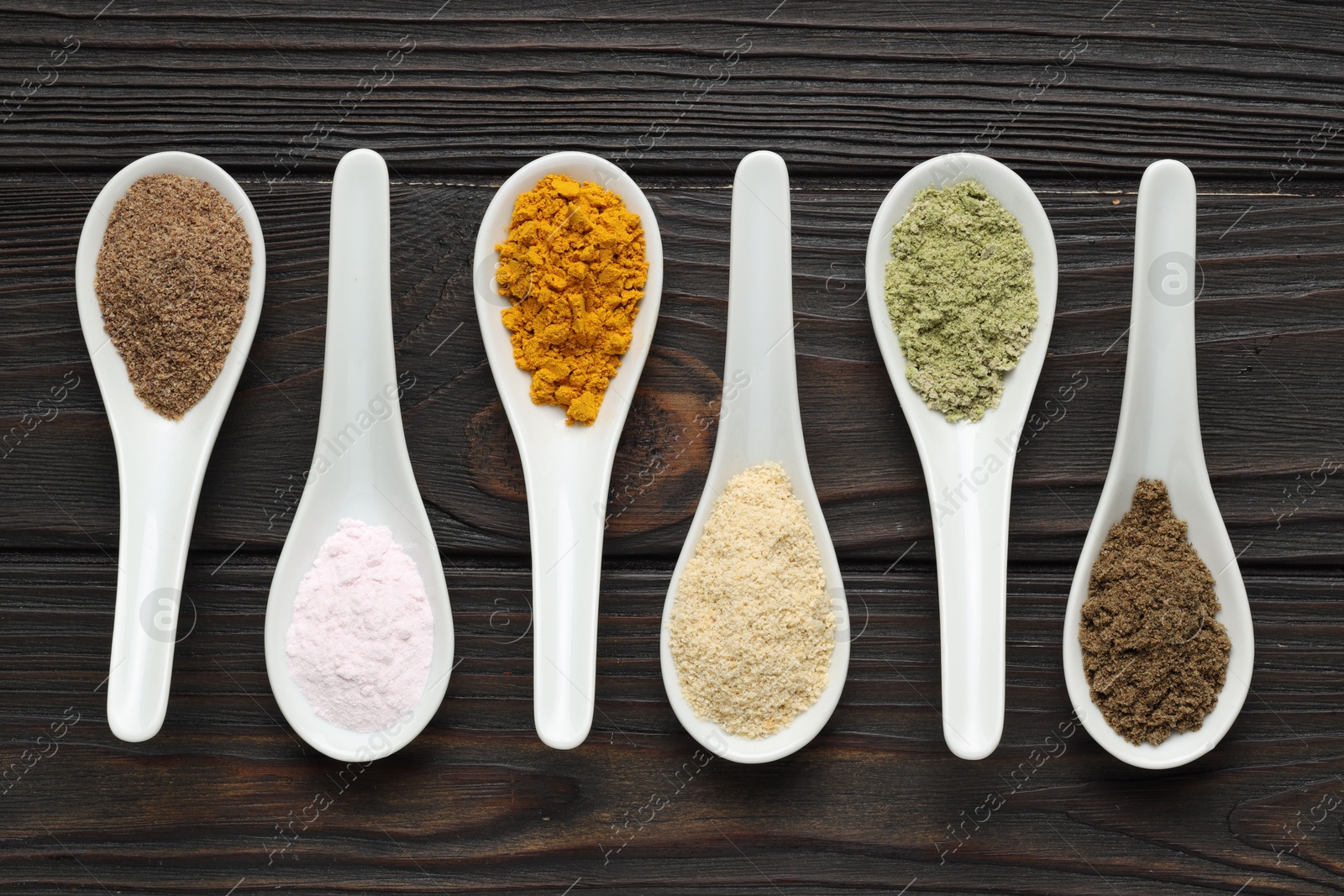 Different superfood powders in spoons on wooden table, flat lay Photo of Different superfood powders in spoons on wooden table, flat lay
