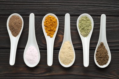 Photo of Different superfood powders in spoons on wooden table, flat lay