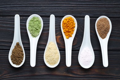 Photo of Different superfood powders in spoons on wooden table, flat lay
