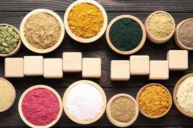 Photo of Different superfood products and blank cubes on wooden table, flat lay