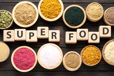 Photo of Cubes with words Super Food, seeds and supplements on wooden table, flat lay