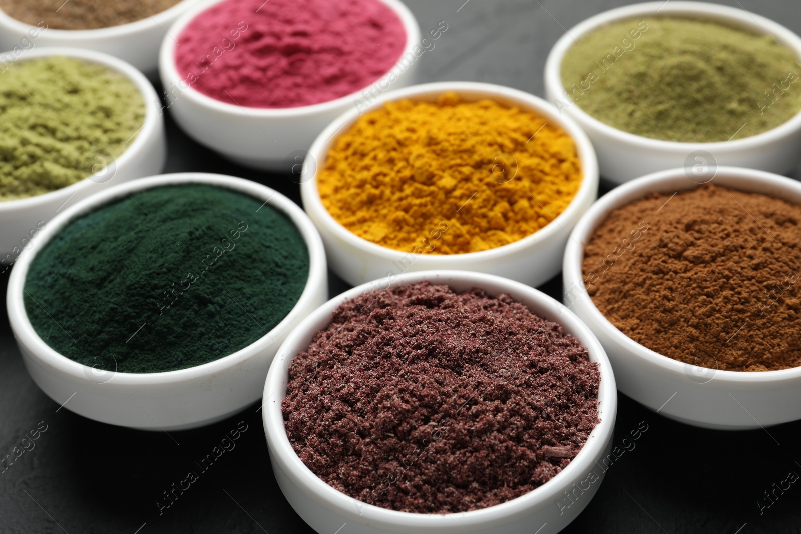 Different superfood powders in bowls on dark table, closeup Photo of Different superfood powders in bowls on dark table, closeup
