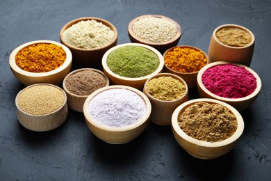 Photo of Different superfood powders in bowls on dark textured table