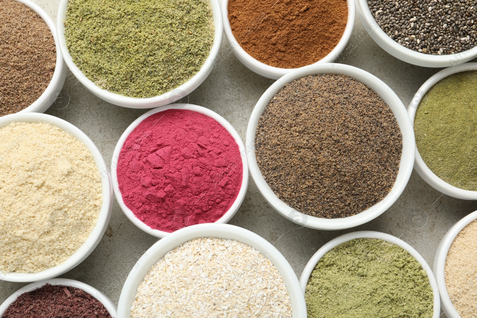 Different superfood powders in bowls on grey textured table, flat lay Photo of Different superfood powders in bowls on grey textured table, flat lay