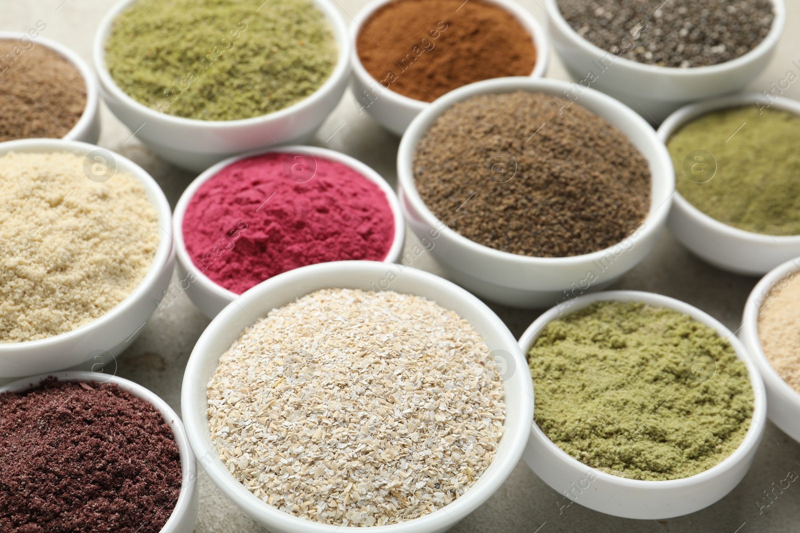 Different superfood powders in bowls on grey textured table, closeup Photo of Different superfood powders in bowls on grey textured table, closeup