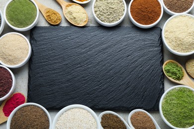 Photo of Different superfood powders and slate board on grey textured table, flat lay. Space for text