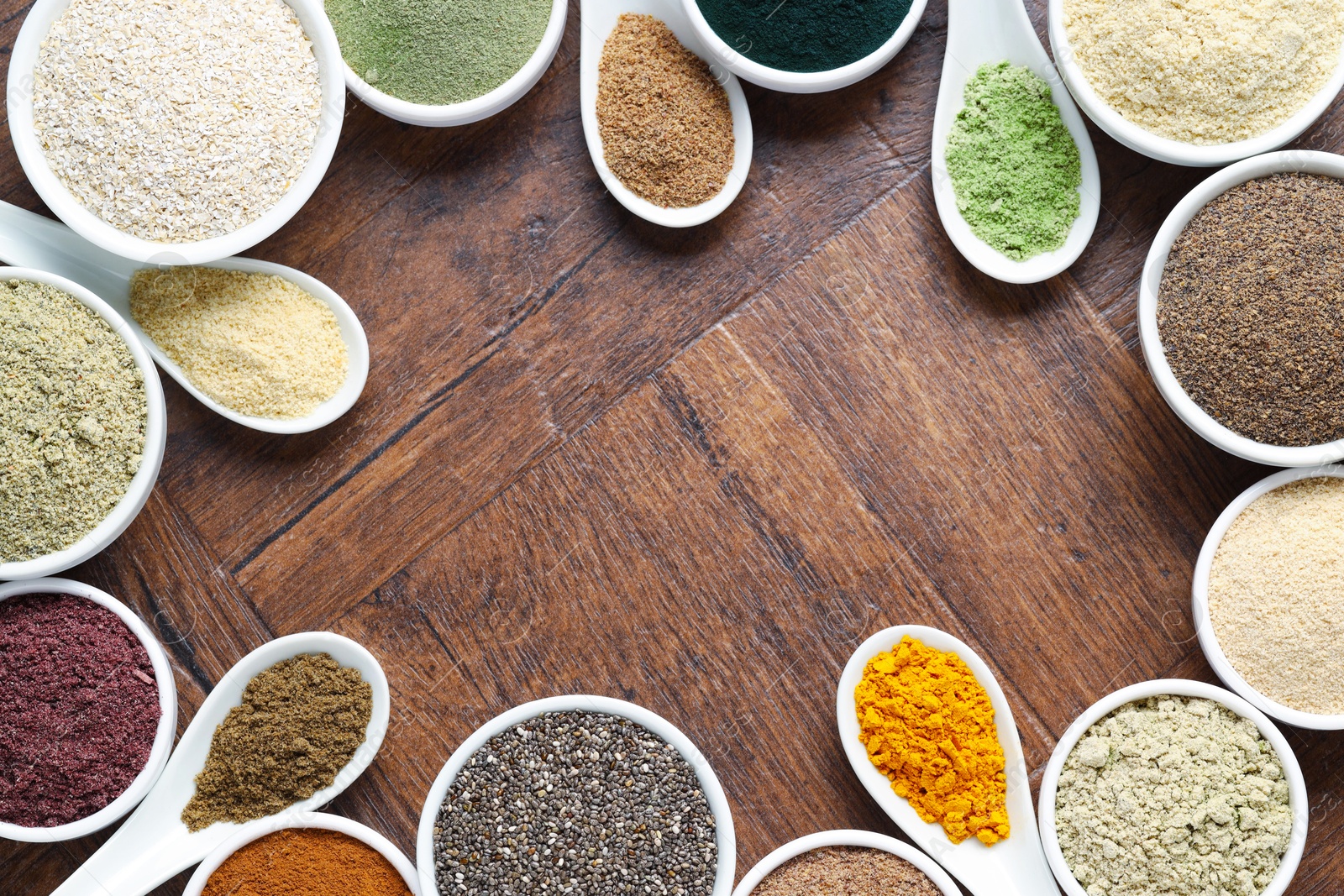 Frame of different superfood powders in bowls and spoons on wooden table, flat lay. Space for text Photo of Frame of different superfood powders in bowls and spoons on wooden table, flat lay. Space for text