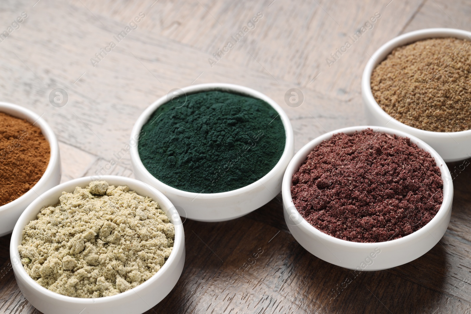 Different superfood powders in bowls on wooden table, closeup Photo of Different superfood powders in bowls on wooden table, closeup