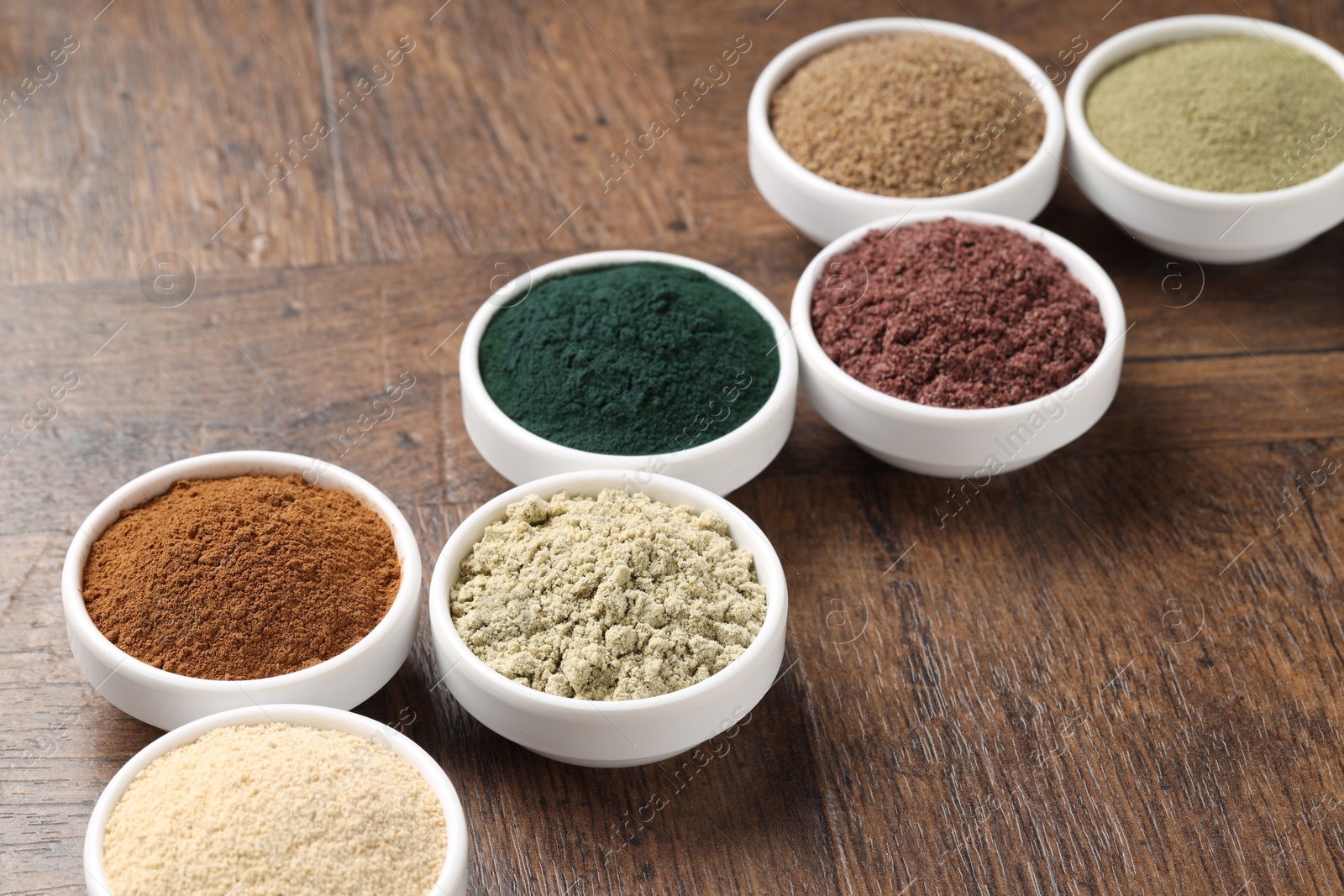 Different superfood powders in bowls on wooden table, closeup Photo of Different superfood powders in bowls on wooden table, closeup