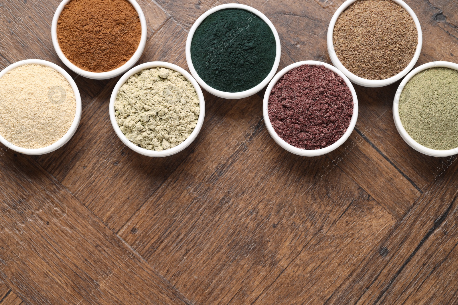 Different superfood powders in bowls on wooden table, flat lay. Space for text Photo of Different superfood powders in bowls on wooden table, flat lay. Space for text