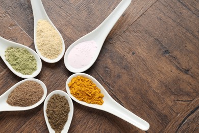 Photo of Different superfood powders in spoons on wooden table, flat lay. Space for text