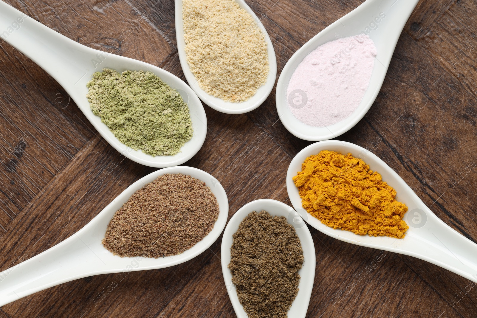 Different superfood powders in spoons on wooden table, flat lay Photo of Different superfood powders in spoons on wooden table, flat lay