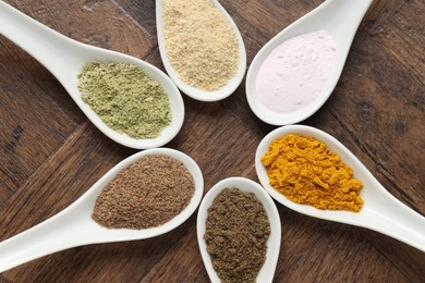 Photo of Different superfood powders in spoons on wooden table, flat lay