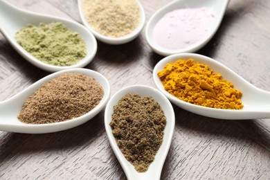 Photo of Different superfood powders in spoons on wooden table, closeup