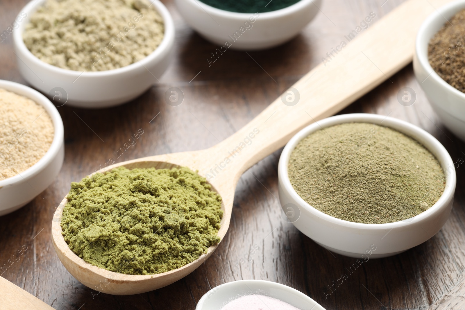 Different superfood powders in bowls and spoons on wooden table, closeup Photo of Different superfood powders in bowls and spoons on wooden table, closeup