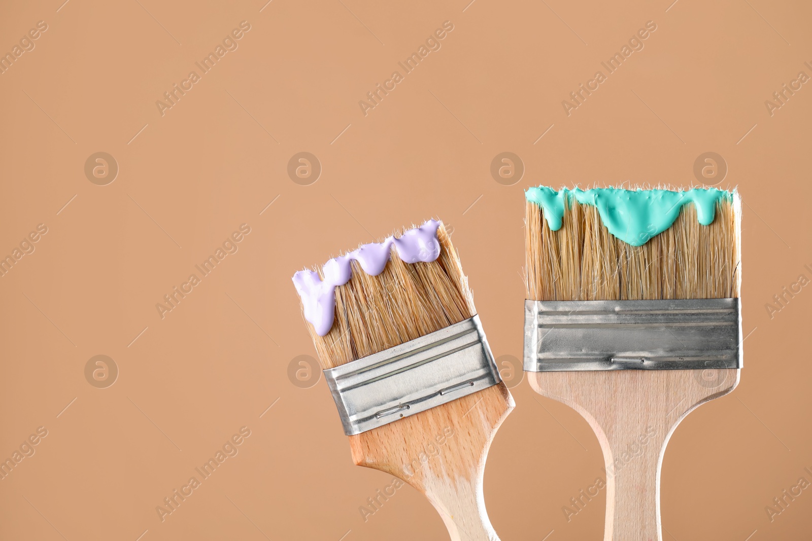 Two brushes with color paints on light brown background, closeup. Space for text Photo of Two brushes with color paints on light brown background, closeup. Space for text