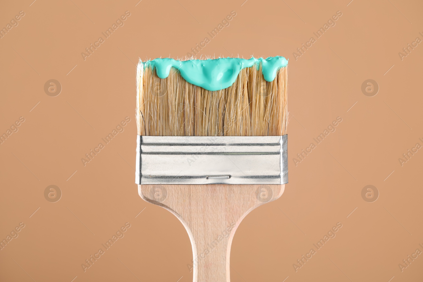 Brush with turquoise paint on light brown background, closeup Photo of Brush with turquoise paint on light brown background, closeup
