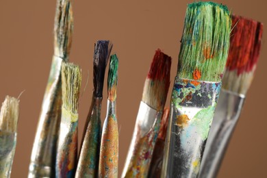 Photo of Dirty paintbrushes on light brown background, closeup