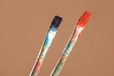 Photo of Dirty paintbrushes on light brown background, closeup