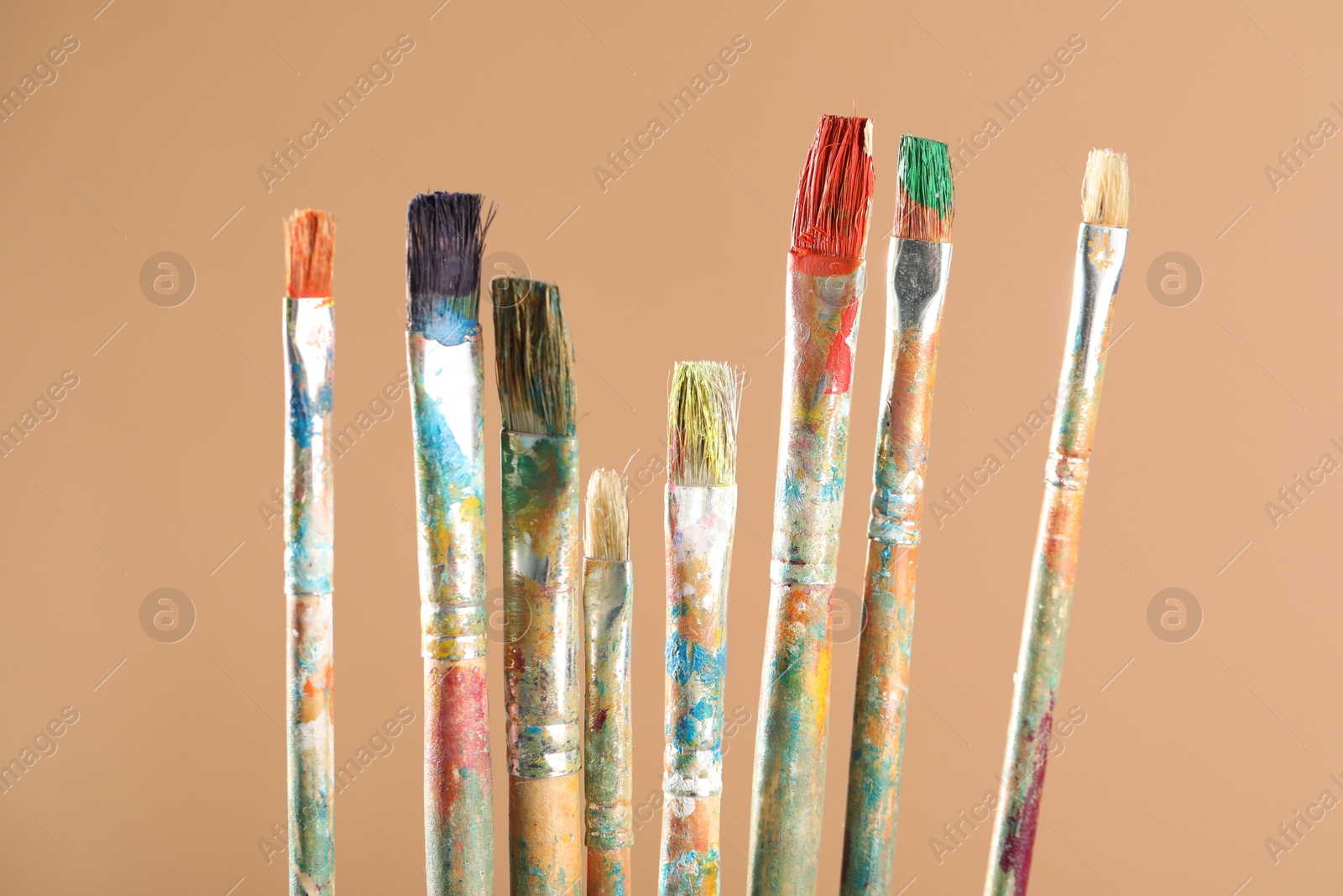 Dirty paintbrushes on light brown background, closeup Photo of Dirty paintbrushes on light brown background, closeup