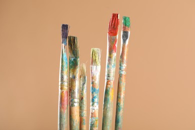 Photo of Dirty paintbrushes on light brown background, closeup