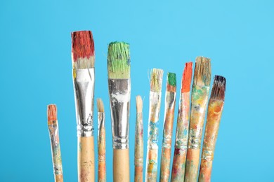 Photo of Dirty paintbrushes on light blue background, closeup