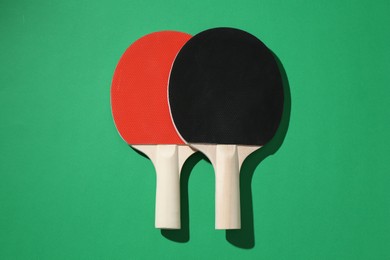 Photo of Ping pong rackets on green background, top view