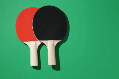 Photo of Ping pong rackets on green background, top view. Space for text