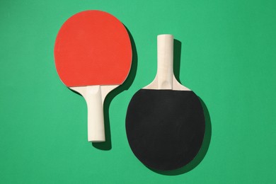 Photo of Ping pong rackets on green background, top view