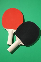 Photo of Ping pong rackets on green background, top view