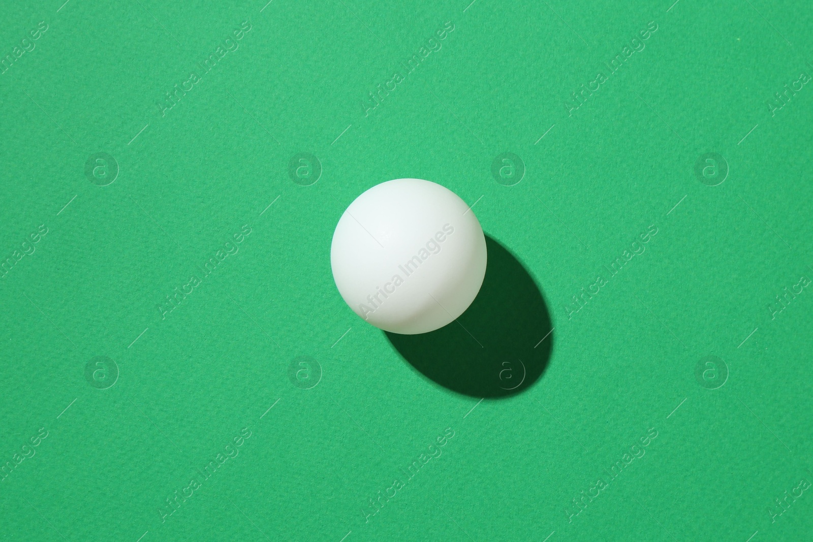 One ping pong ball on green background, top view Photo of One ping pong ball on green background, top view