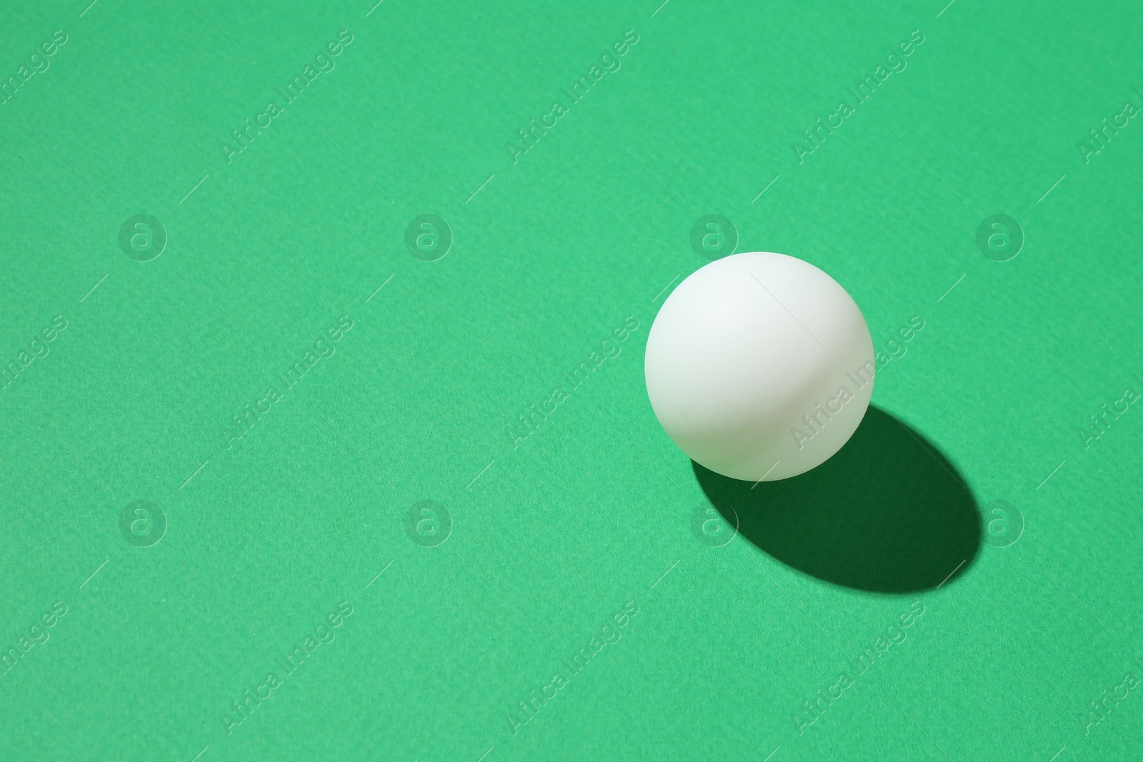 One ping pong ball on green background, closeup. Space for text Photo of One ping pong ball on green background, closeup. Space for text