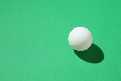 Photo of One ping pong ball on green background, closeup. Space for text