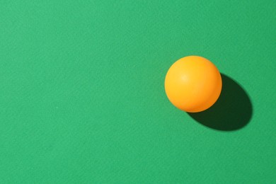 Photo of One ping pong ball on green background, top view. Space for text
