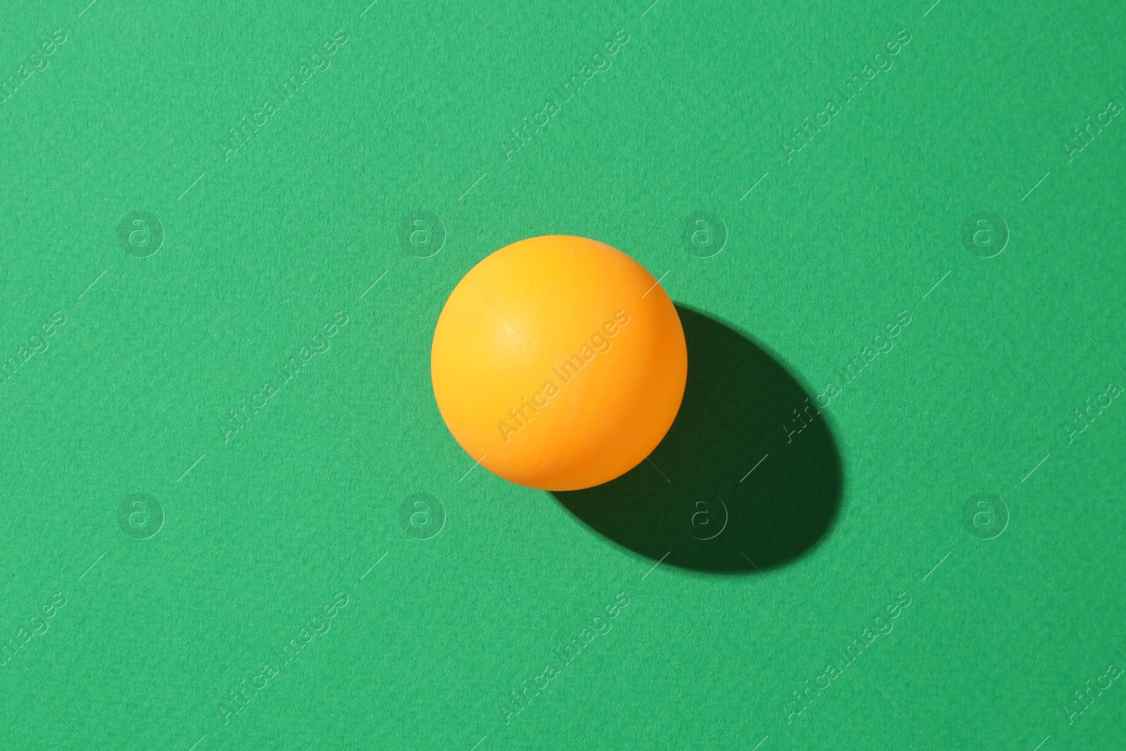 One ping pong ball on green background, top view Photo of One ping pong ball on green background, top view