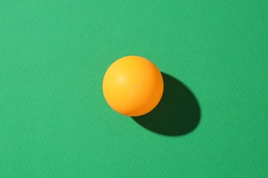 Photo of One ping pong ball on green background, top view