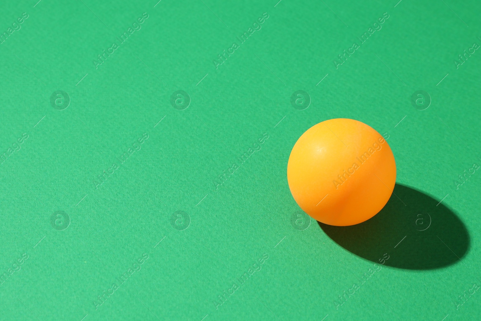 One ping pong ball on green background, closeup. Space for text Photo of One ping pong ball on green background, closeup. Space for text