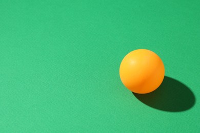 Photo of One ping pong ball on green background, closeup. Space for text
