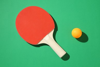Photo of Ping pong racket and ball on green background, top view