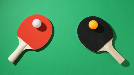 Photo of Ping pong rackets and balls on green background, flat lay