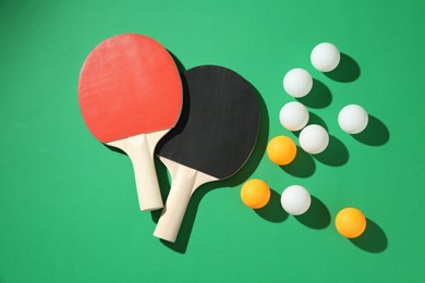 Photo of Ping pong rackets and balls on green background, flat lay