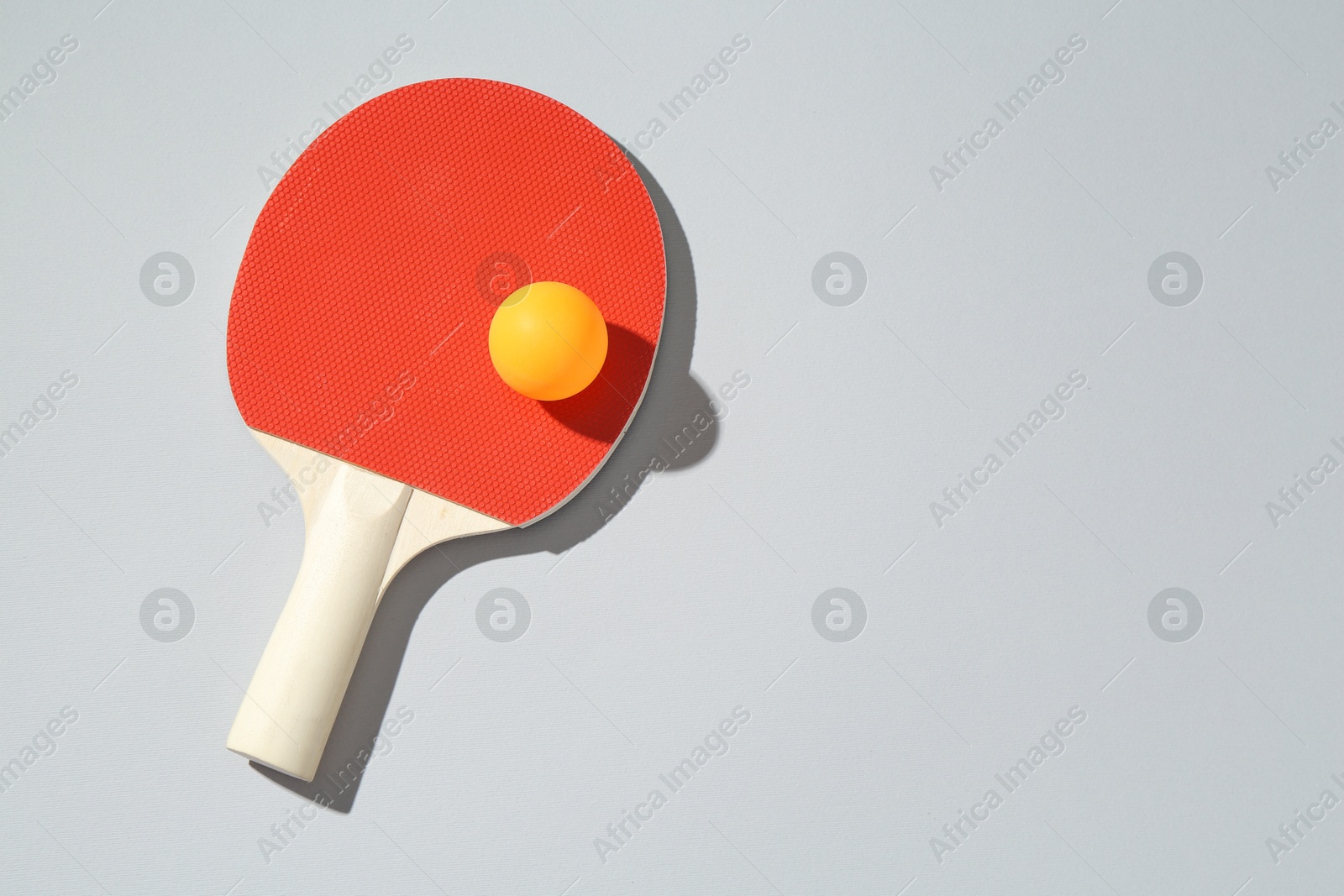 Ping pong racket and ball on light background, top view. Space for text Photo of Ping pong racket and ball on light background, top view. Space for text