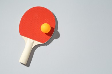 Photo of Ping pong racket and ball on light background, top view. Space for text